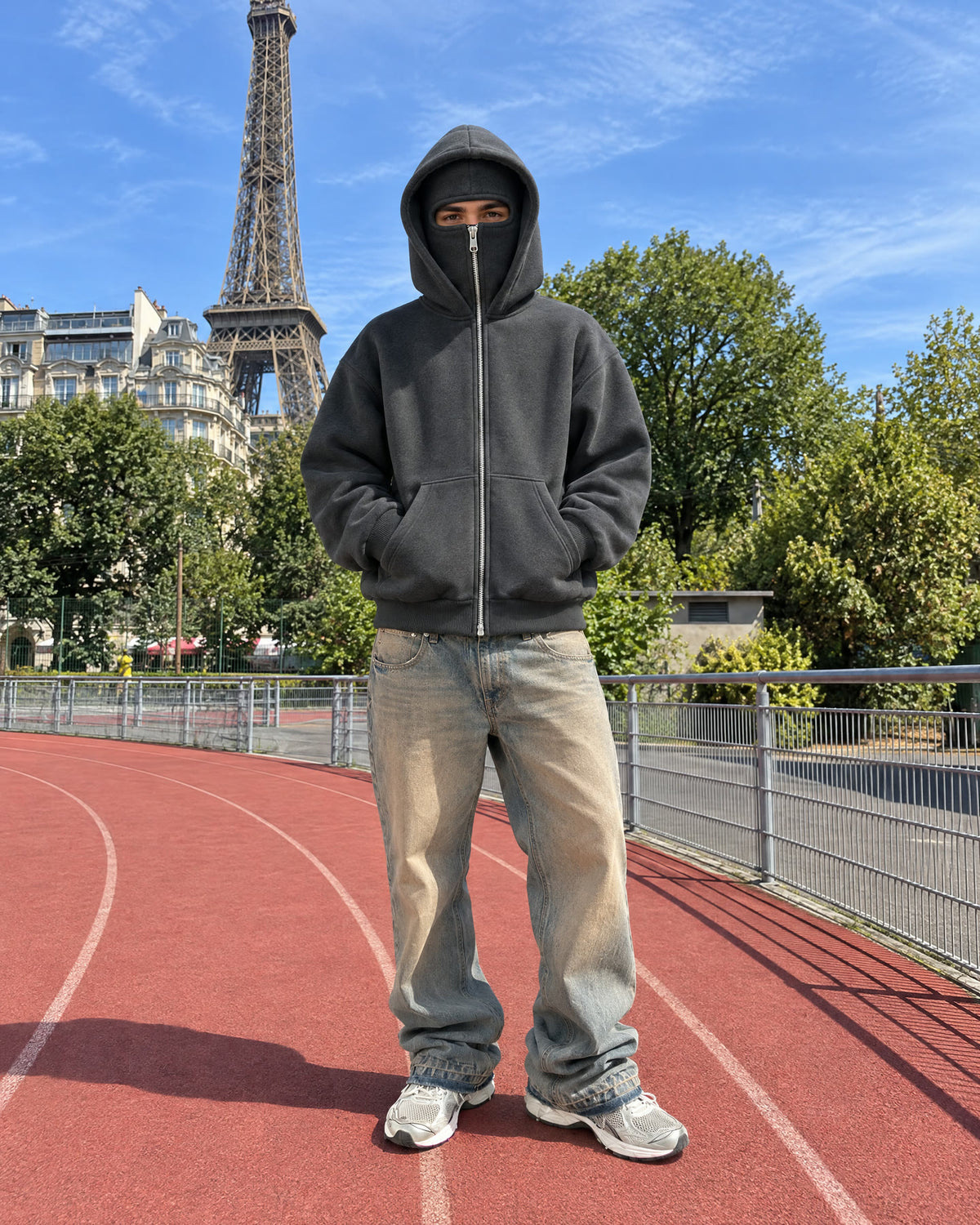 Sweat NOFACE PARIS gris foncé porté, cagoule fermée, devant la tour Eiffel